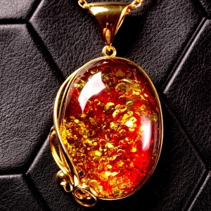 Ciondolo in ambra rosso cognac: gemma con inclusioni dorate, eleganza senza tempo.