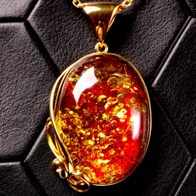 Ciondolo in ambra rosso cognac: gemma con inclusioni dorate, eleganza senza tempo.