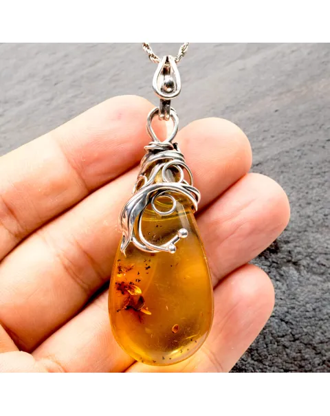 Ciondolo in argento con ambra color miele: eleganza naturale e storia antica.