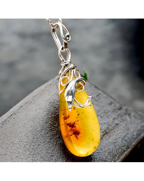 Ciondolo in argento con ambra color miele: eleganza naturale e storia antica.