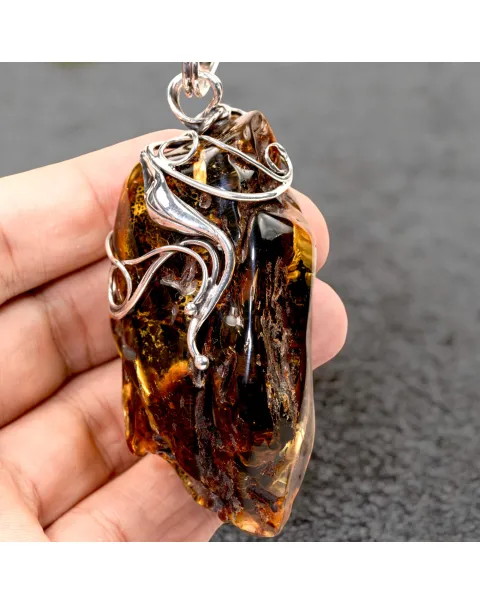 Ciondolo in argento con ambra grezza color cognac: connessione con la natura e protezione spirituale.