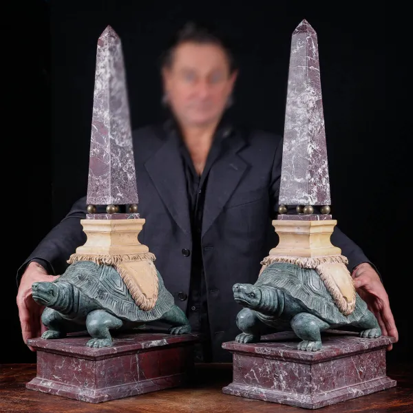 Coppia di obelischi in marmo con base scultorea a forma di tartaruga.