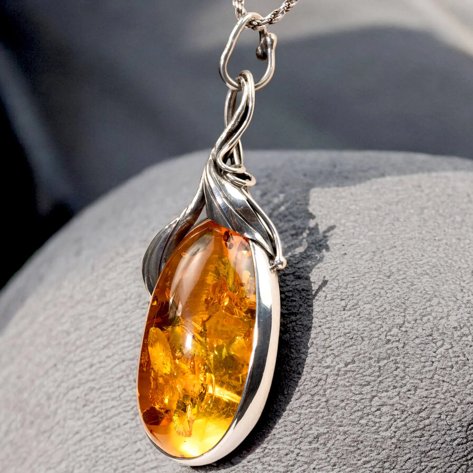 Ciondolo in argento con ambra color miele e inclusioni a forma di petali: eleganza naturale e armonia.