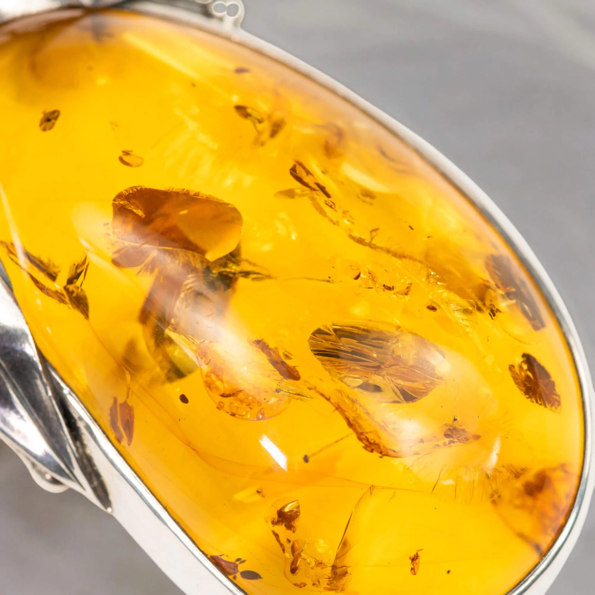 Ciondolo in argento con ambra color miele e inclusioni a forma di petali: eleganza naturale e armonia.