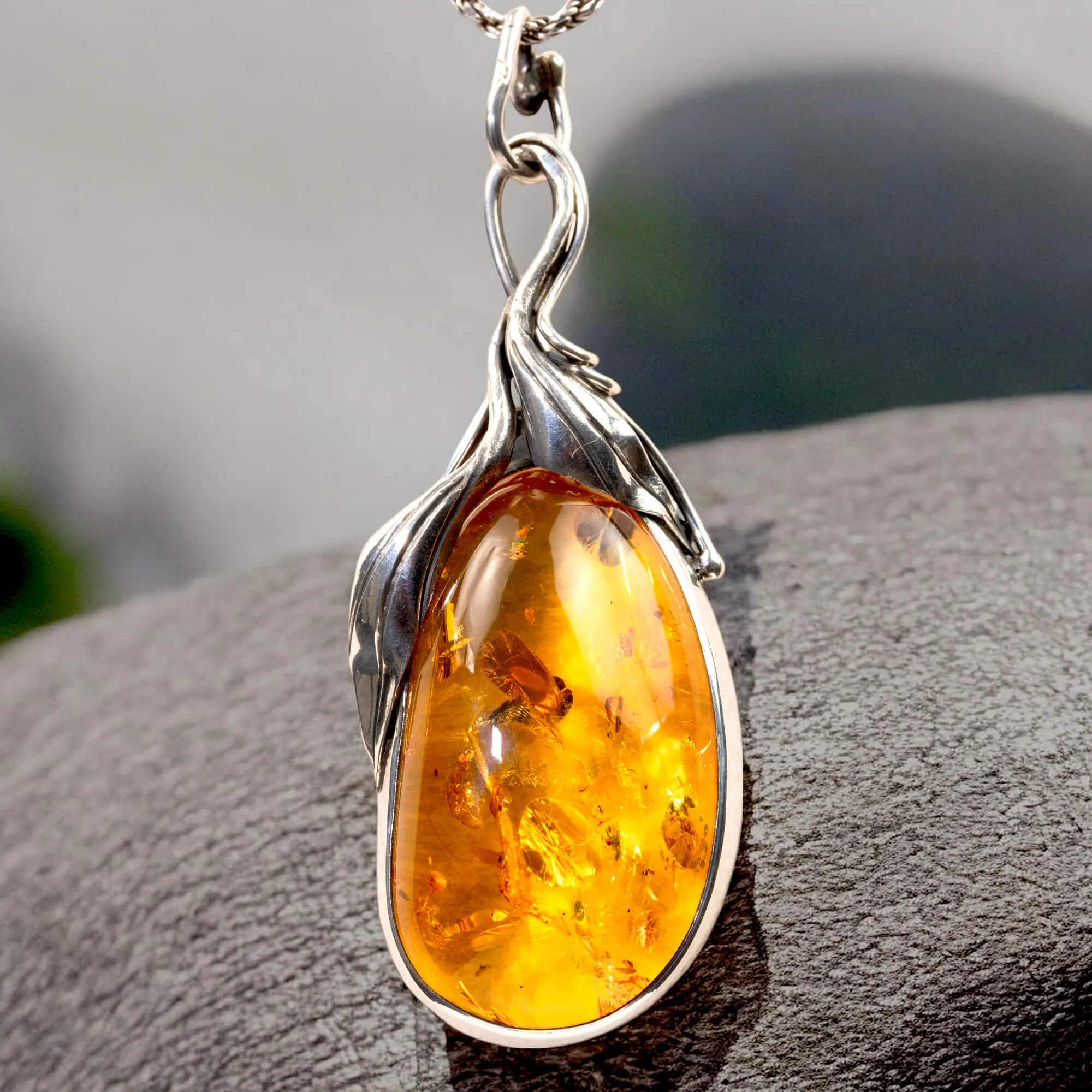 Ciondolo in argento con ambra color miele e inclusioni a forma di petali: eleganza naturale e armonia.