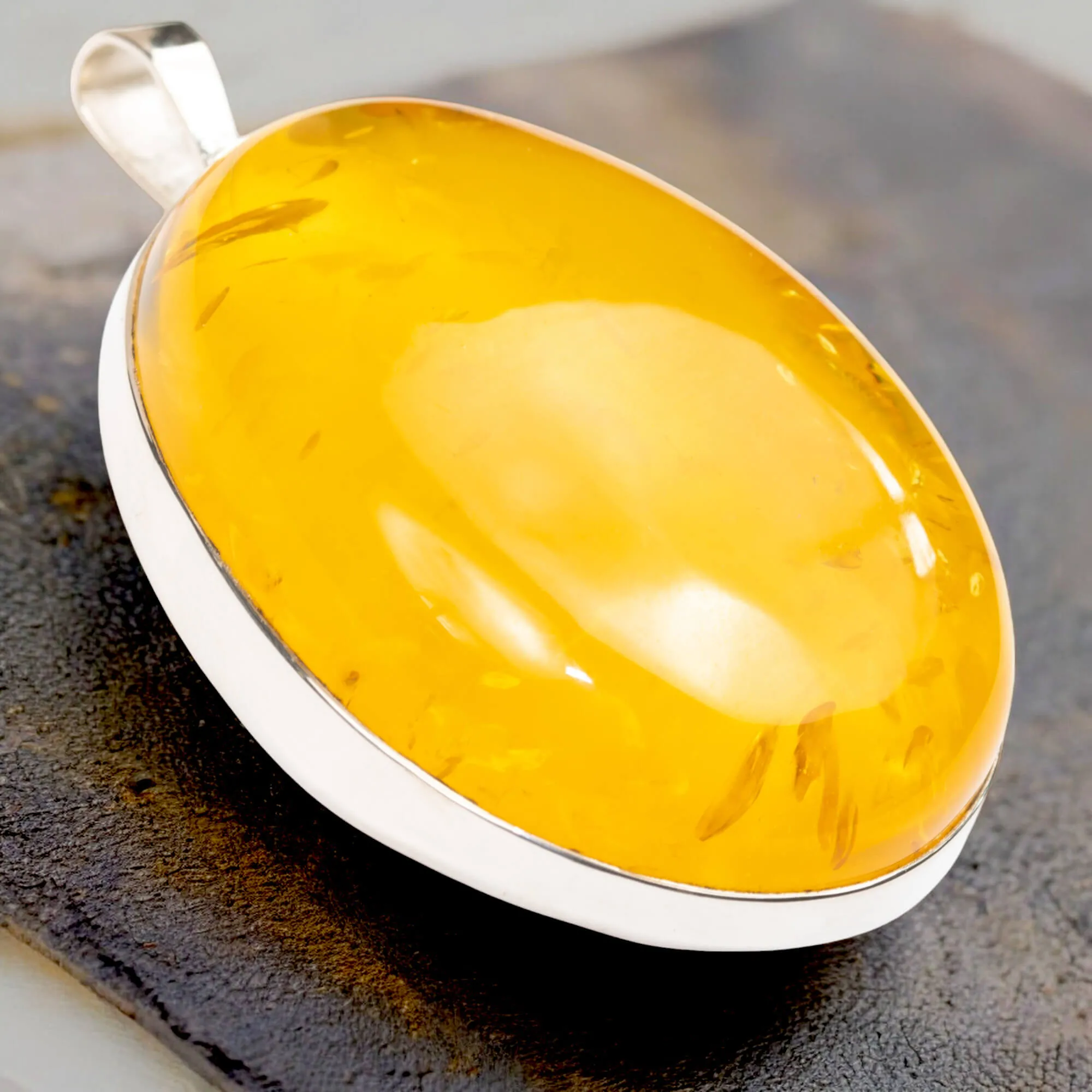 Ciondolo in argento con ambra color miele: eleganza e protezione energetica.
