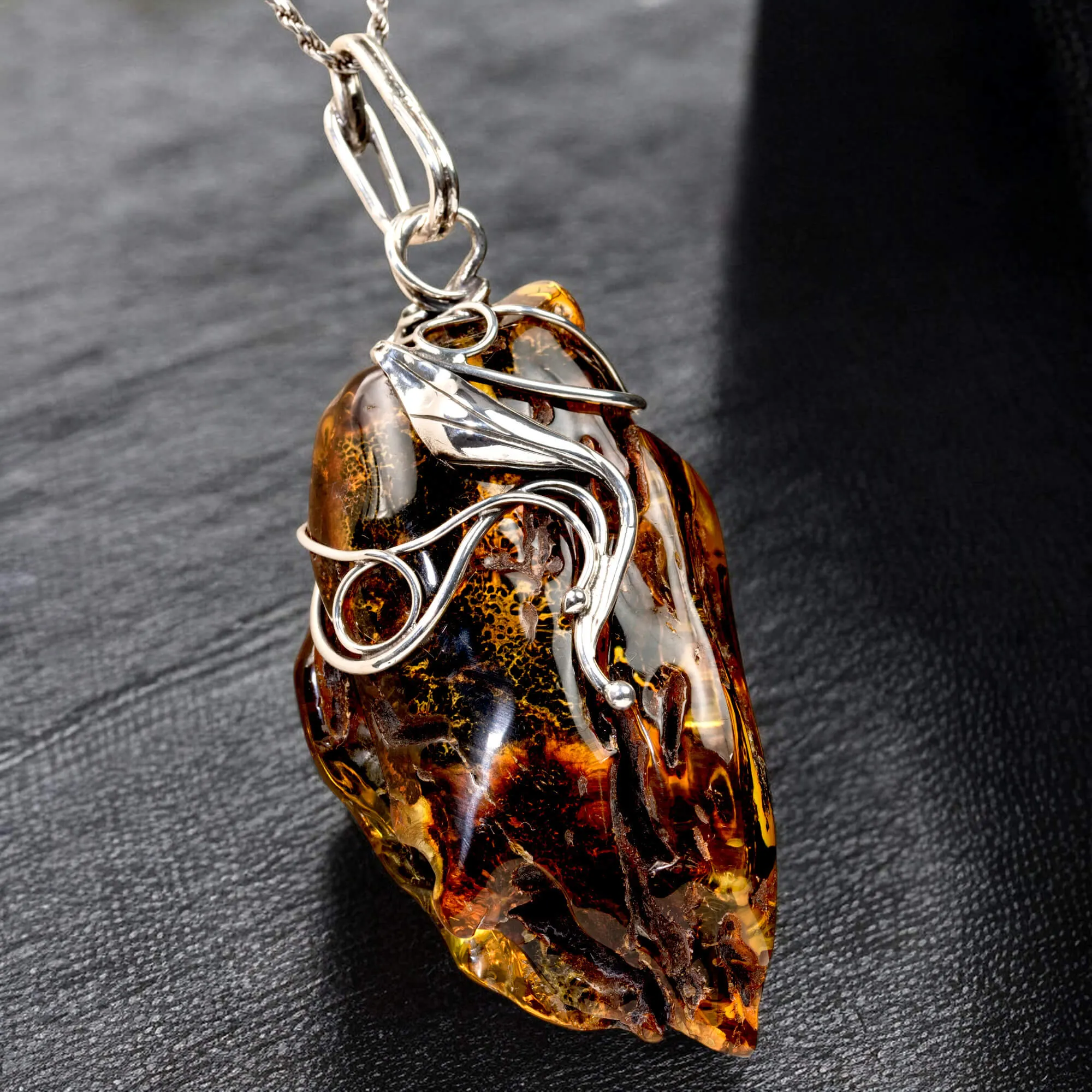Ciondolo in argento con ambra grezza color cognac: connessione con la natura e protezione spirituale.