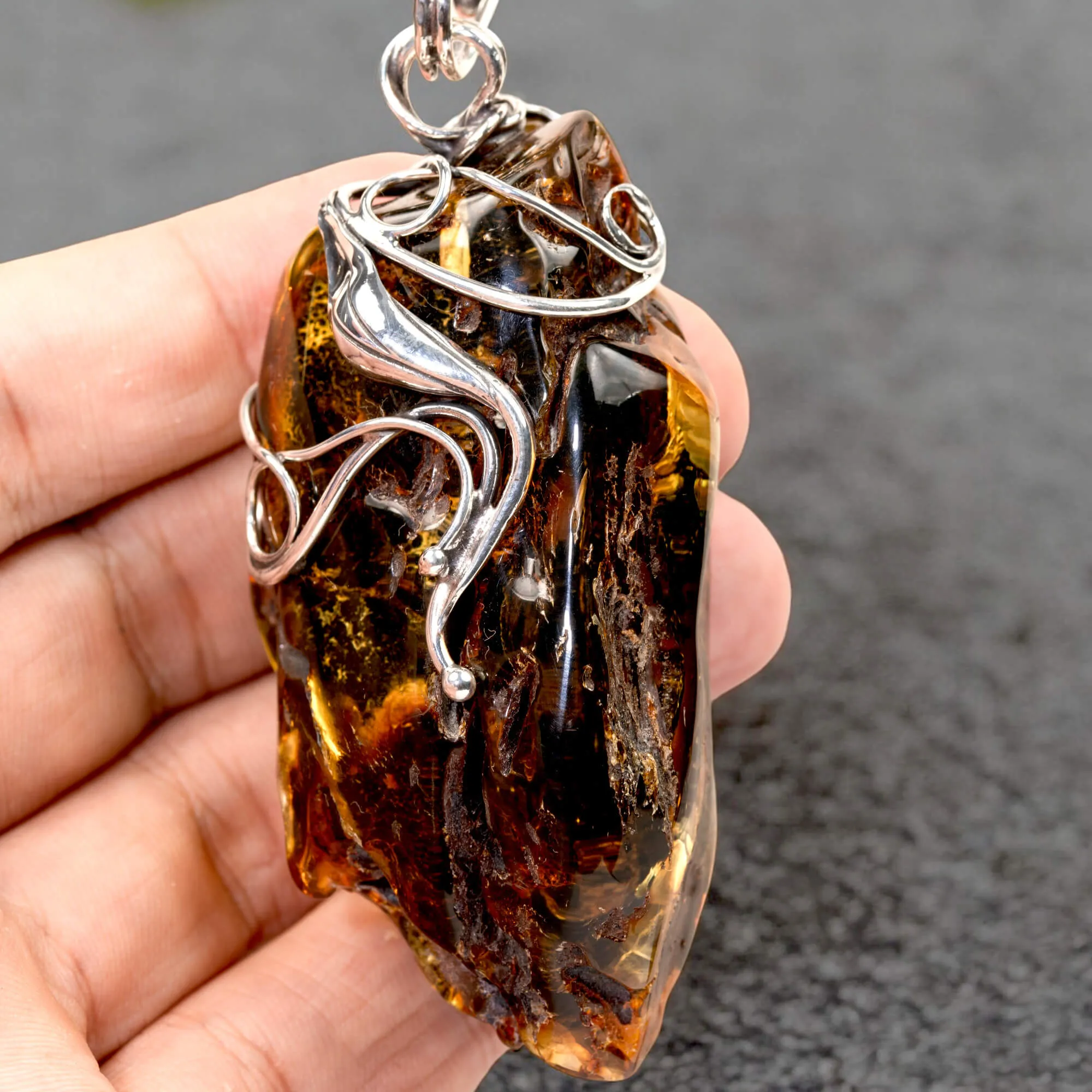 Ciondolo in argento con ambra grezza color cognac: connessione con la natura e protezione spirituale.