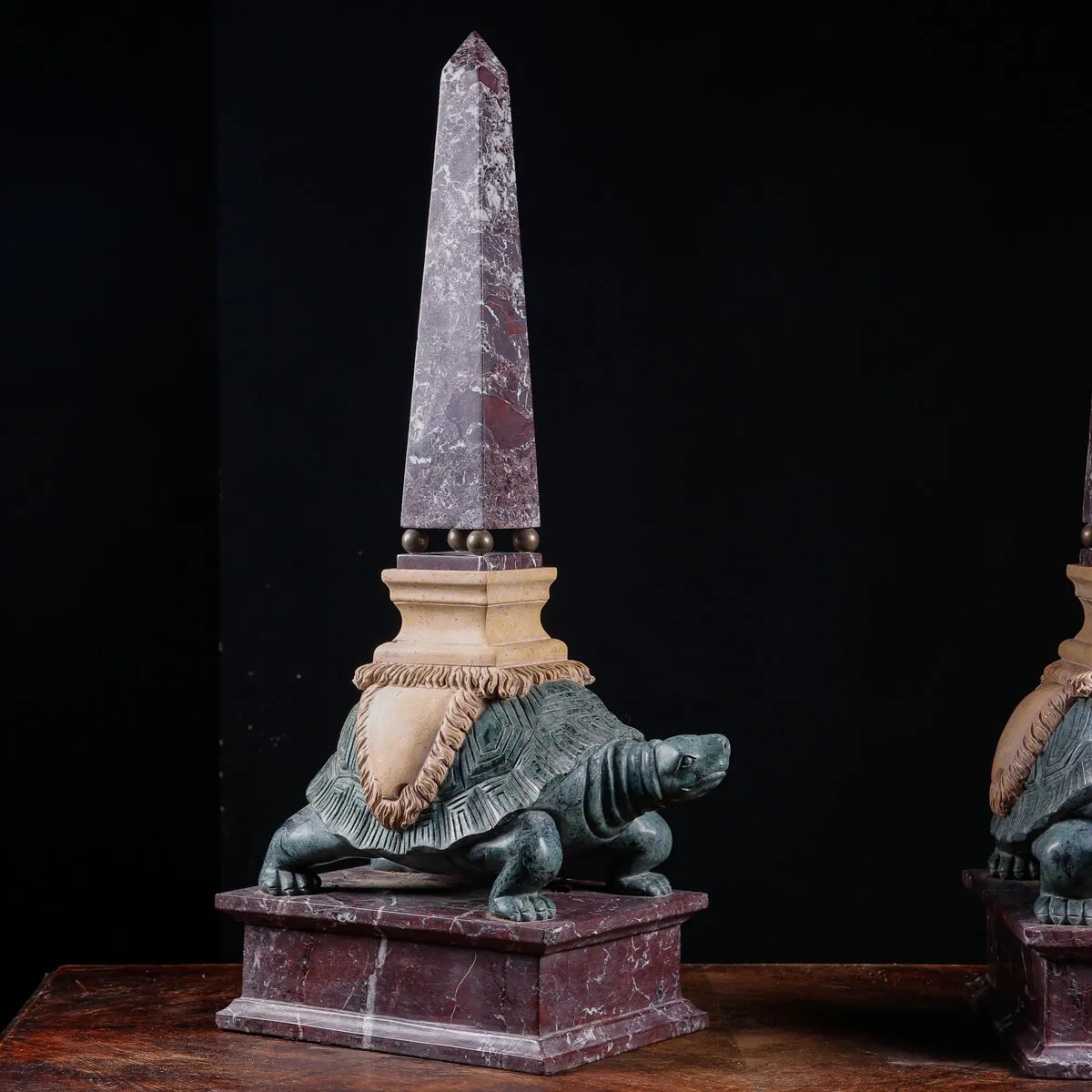 Coppia di obelischi in marmo con base scultorea a forma di tartaruga.